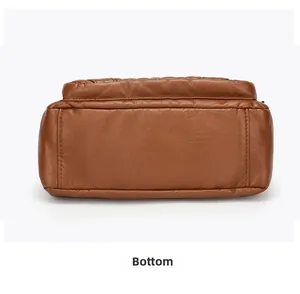 Detail view of the wide bottom with litchi texture on a brown shoulder bag