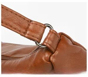 Macro detail of silver D-ring hardware and neat stitching on brown textured leather bag