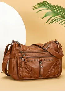Detail of soft brown leather crossbody bag with multiple zippers and woven texture