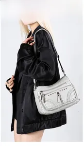Macro detail of soft grey faux leather crossbody bag with woven texture and rivets