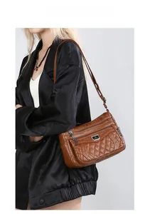 Detail of brown quilted crossbody bag featuring multiple zipper pockets and silver metal logo