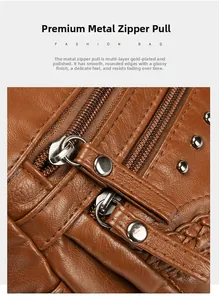 Detail of brown litchi grain leather bag showing high-quality polished gold metal zippers