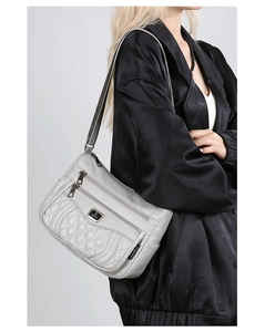 Close-up of a light grey quilted shoulder bag with multi-zipper pockets and metal logo