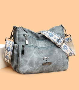 Close-up of retro gray-blue tote bag featuring multiple zippers and ethnic pattern strap