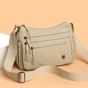Minimalist beige nylon tote bag with multiple zip pockets and adjustable shoulder strap