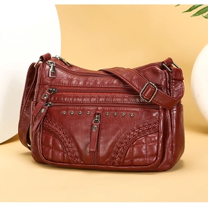 Detail of burgundy soft leather crossbody bag with multiple zippers and woven texture