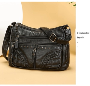 Detail of black soft leather crossbody bag with multiple zippers and rivet accents