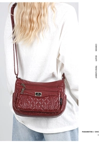 Detail of burgundy quilted cowhide leather bag with silver zipper and sport metal plaque
