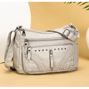 Close-up of soft faux leather crossbody bag with multi-zipper pockets and rivet details