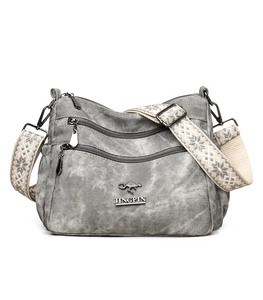 Detail of grey canvas crossbody bag with vintage texture and patterned wide shoulder strap