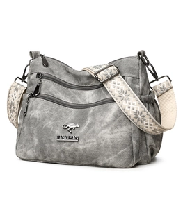 Detail of grey crossbody bag featuring textured fabric and ethnic geometric strap