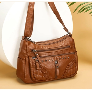 Detail of brown PU leather crossbody bag with multiple zippers and woven texture accents