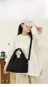 Detail of a black canvas multi-pocket tool bag shown on shoulder with wide strap
