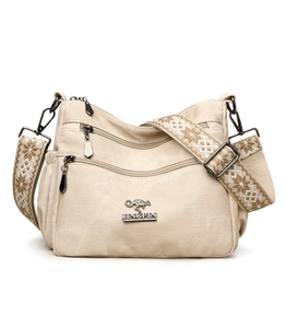 Macro view of beige canvas crossbody bag with multi-zipper pockets and jacquard strap