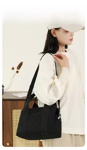 Chic black canvas crossbody bag styled on shoulder in a warm minimalist home setting