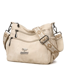 Detail of beige tote bag showing multi-zipper layers and jacquard weave strap