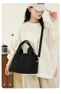Detail of black canvas tote bag with wide handles and adjustable nylon shoulder strap