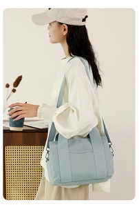 Detailed shot of a light blue canvas tool bag with adjustable shoulder strap and handle
