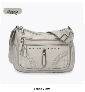 Front view of grey multi-zipper leather crossbody bag with woven details and studs