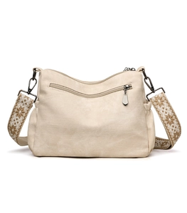 Detail of beige canvas tote bag featuring an ethnic embroidered wide shoulder strap