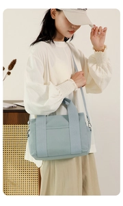 Detail of light blue canvas tote bag featuring reinforced straps and adjustable shoulder strap