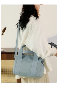 Light blue canvas tool bag shown from a side-back view on a model in a warm interior