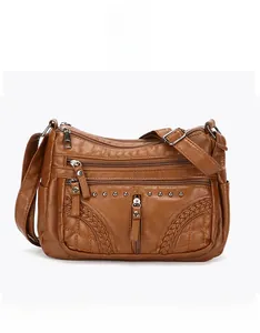 Detailed front view of brown multi-zippered PU leather crossbody bag with woven details