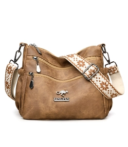 Close-up of brown faux leather tote with triple front zippers and ethnic woven strap