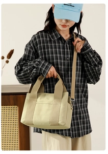Detail of beige canvas crossbody bag with adjustable strap worn by a model in casual style