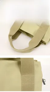Detail of beige canvas tool bag showing reinforced X-stitching and metal D-ring hook