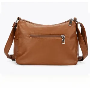 Rear view of brown textured leather crossbody bag showing silver zipper pocket and strap