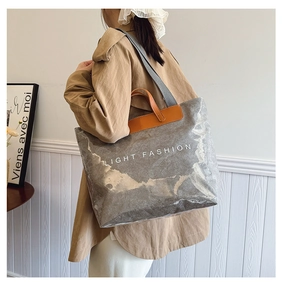 Détail du sac cabas argenté métallisé avec couche PVC et poignées en cuir marron