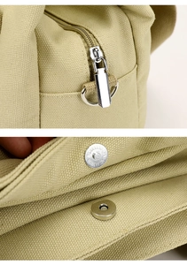Detail of silver metal zipper with D-ring and magnetic snap closure on canvas bag