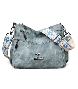 Close-up of vintage blue canvas tote bag with metal logo and ethnic woven strap