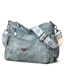 Detail of grey washed denim crossbody bag with multi-pocket layout and jacquard strap