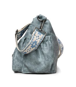 Close-up of blue denim tote bag with ethnic embroidery strap and textured pleats