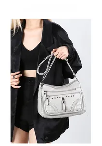 Detail view of light grey soft leather crossbody bag with woven trim and multi-layer zippers