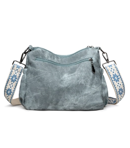 Detail of light blue-grey canvas crossbody bag with ethnic snowflake pattern strap