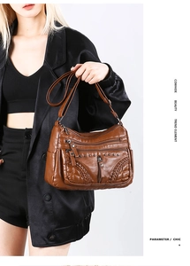 Detail of brown cowhide crossbody bag with dual zippers and woven texture on a model