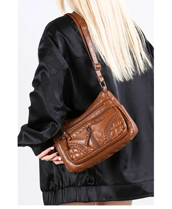 Detailed back view of a brown soft leather crossbody bag with woven texture and rivets