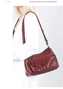 Detail view of wine red soft leather crossbody bag with multiple zipper compartments