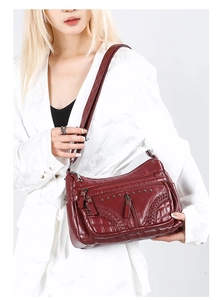 Detail view of burgundy soft leather crossbody bag with multi-layer zipper pockets