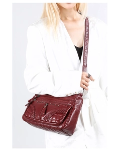 Detailed view of wine red soft leather crossbody bag with multiple zip compartments