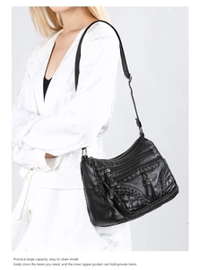 Side view of black soft leather crossbody bag with multiple zip pockets on model