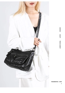 Close-up of black cowhide leather crossbody bag with silver rivets and woven textures