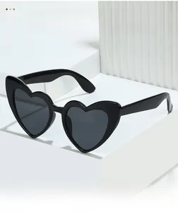 Detail of heart-shaped sunglasses with black glossy frames on a white geometric stand