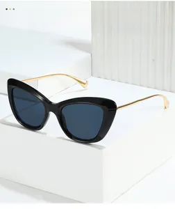 Dettaglio di occhiali da sole cat-eye con stanghette dorate su supporto geometrico