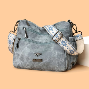 Blue canvas shoulder bag with multi-zipper design and embroidered wide strap