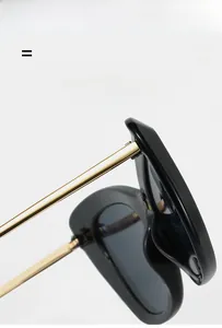 Dettaglio delle stanghette in metallo dorato su occhiali da sole neri cat-eye minimalisti
