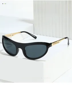 Detail view of cat eye sunglasses with golden hollow-out metal temples on a stone base